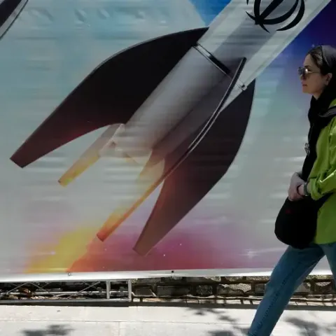 Una mujer pasa junto a un imagen gigante de misiles en Teherán