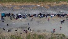 Migrantes duermen junto al muro fronterizo en Tijuana en busca de asilo humanitario
